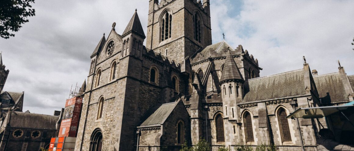 Christ Church Cathedral Dublin in daylight with visitors sitting on the grass outside