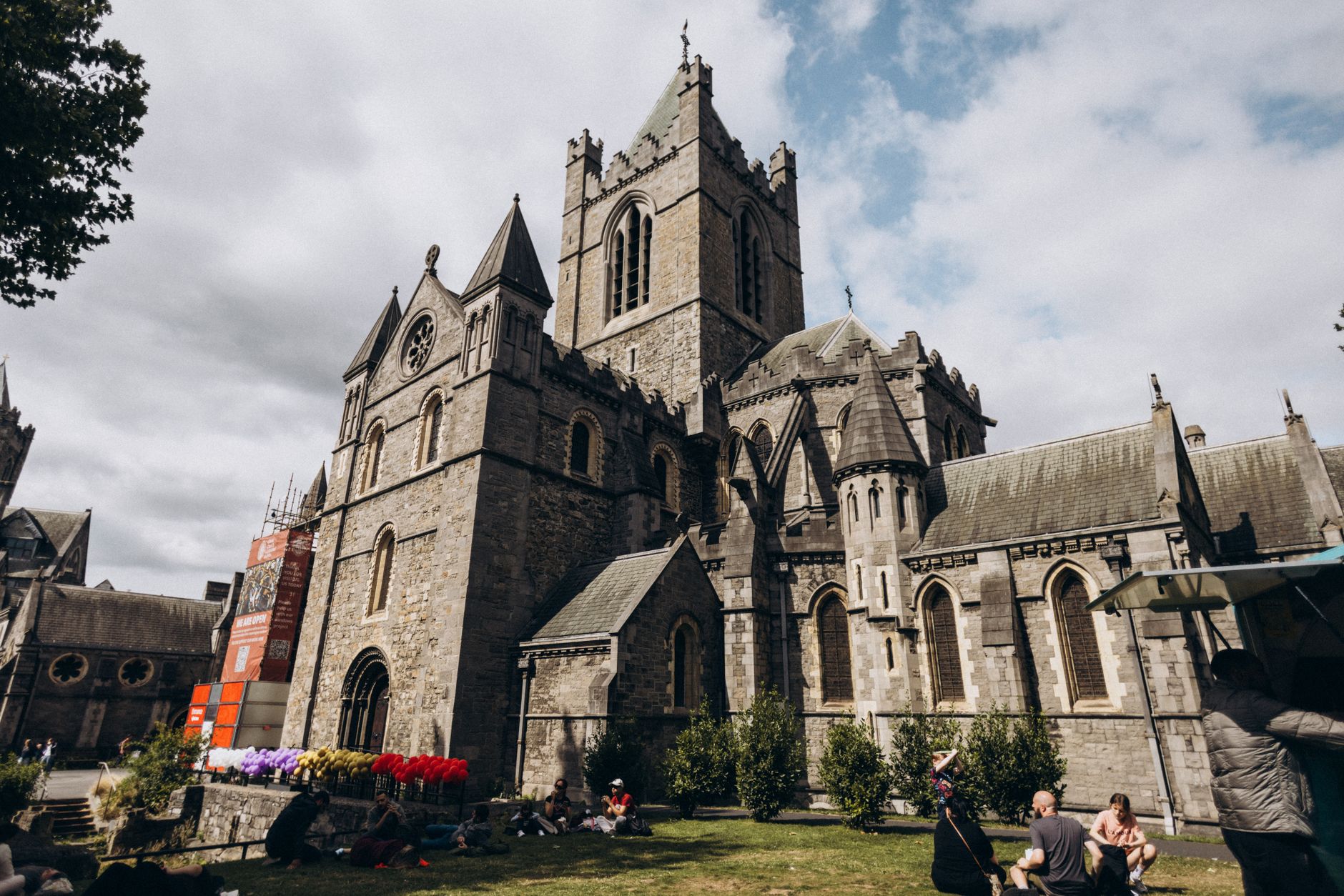 Christ Church Cathedral Dublin in daylight with visitors sitting on the grass outside