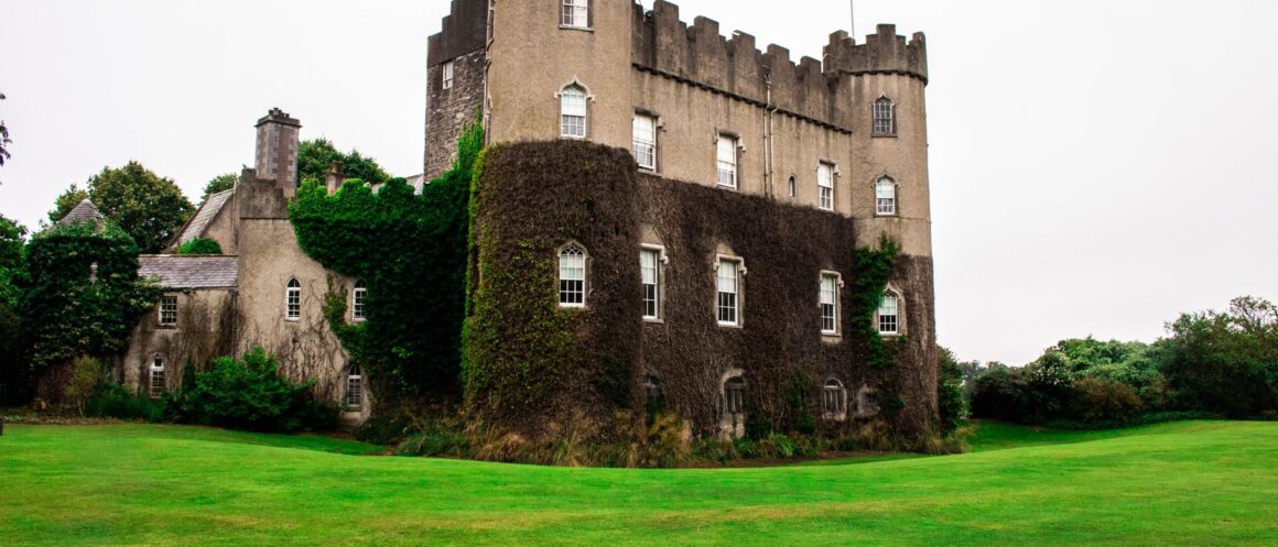 Malahide Castle in north Dublin with ivy-covered round towers above a green lawn