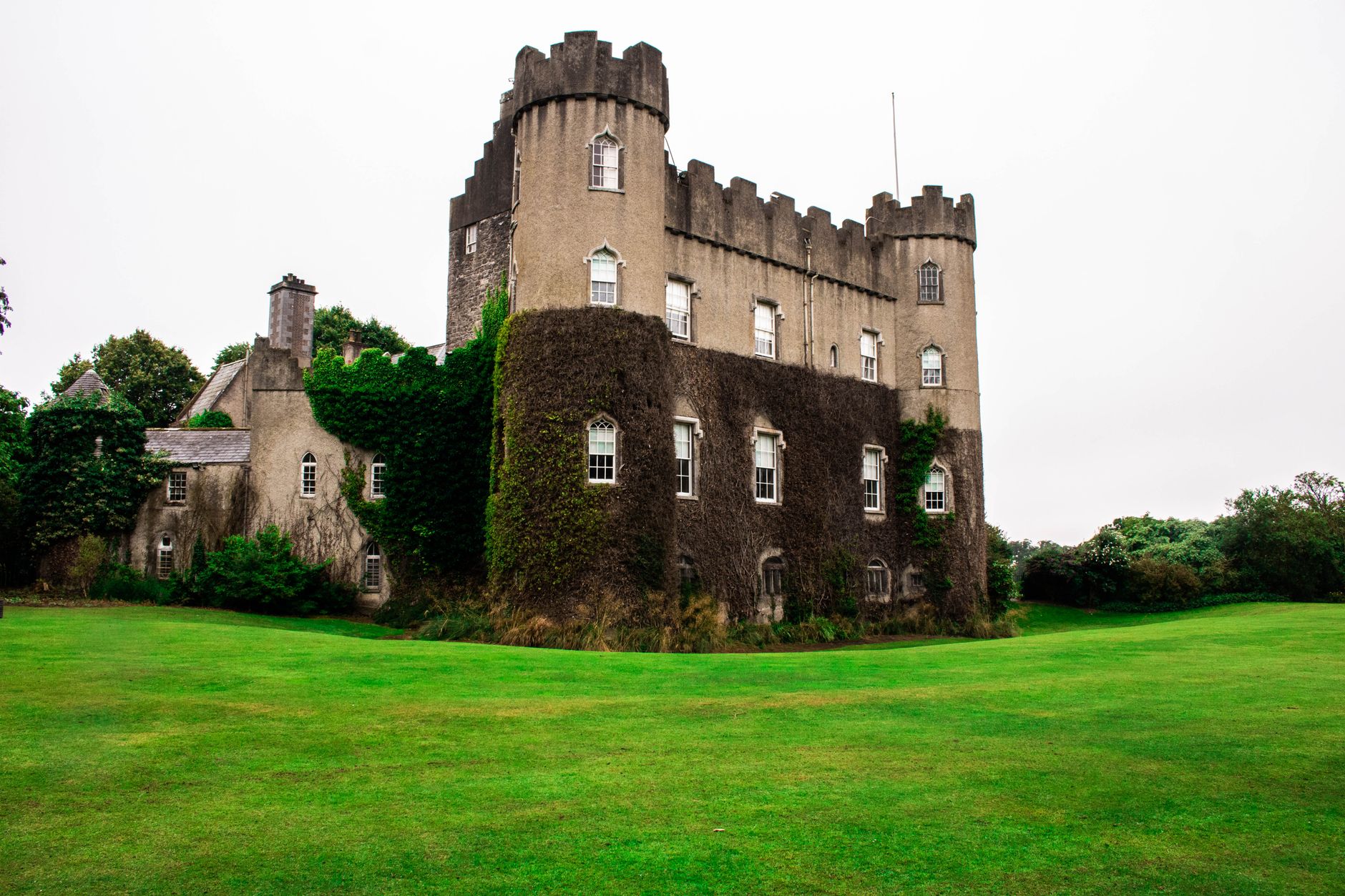 Malahide Castle in north Dublin with ivy-covered round towers above a green lawn
