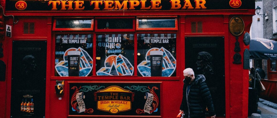 The red facade of The Temple Bar pub in Dublin's Temple Bar district, with a passer-by on the pavement