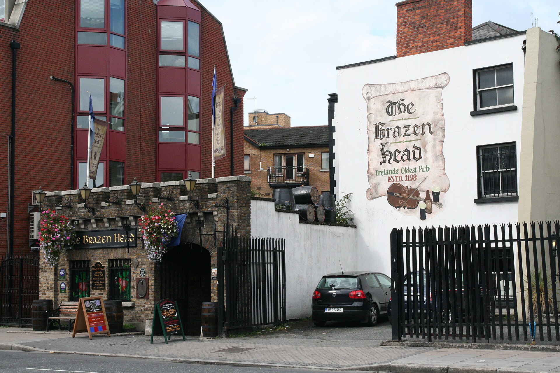 The Brazen Head in Dublin has a stone archway, flower baskets and a large scroll mural on its white wall.