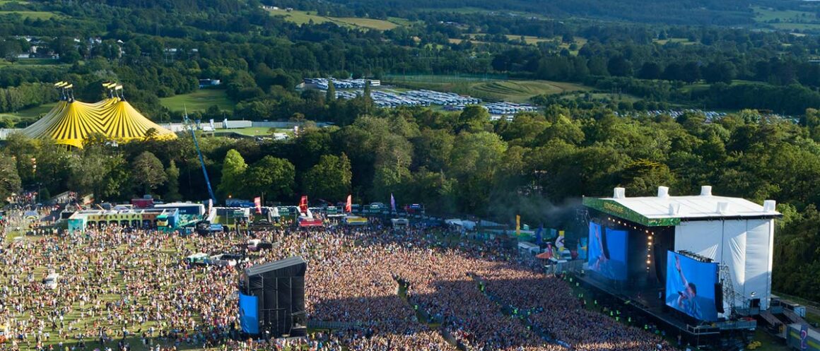 Crowds gather before the main stage at Longitude in Dublin’s Marlay Park, with wooded hills beyond the festival grounds.