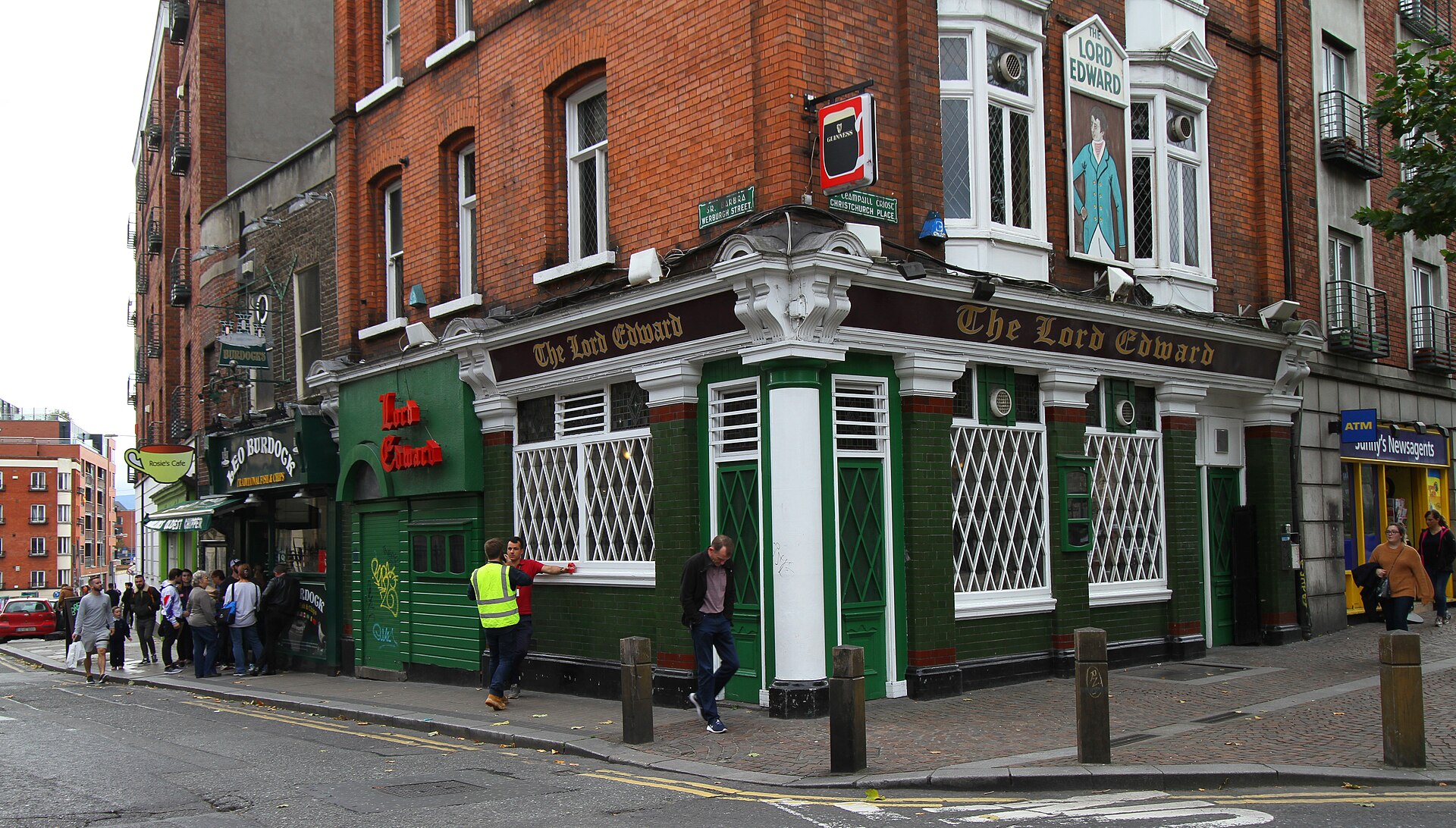 Customers stand outside Leo Burdock’s Dublin fish-and-chip shop beside the green and white corner frontage of the Lord Edward pub.
