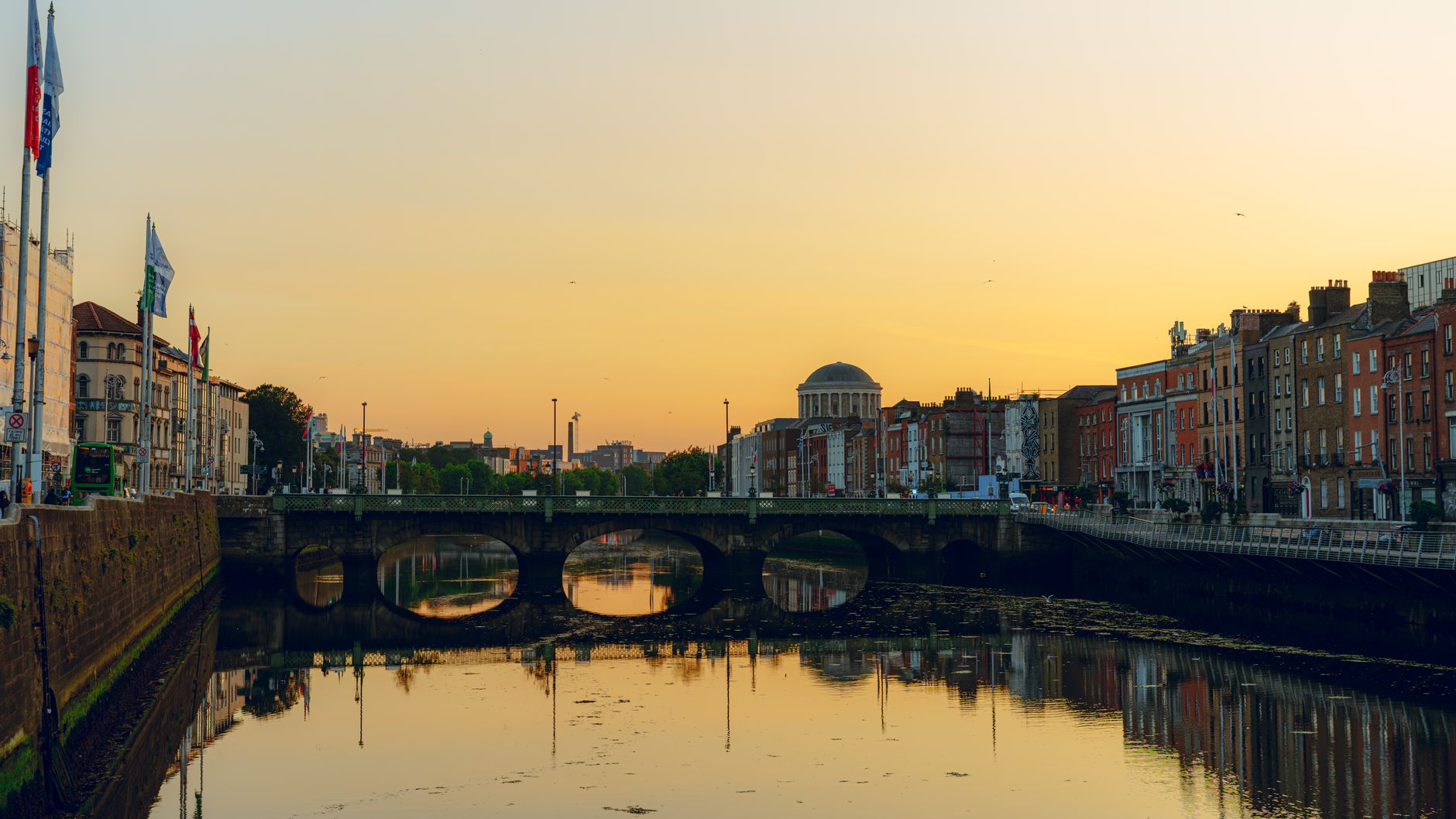 Sunset over the River Liffey in Dublin with the Four Courts dome and a stone bridge reflected in the water