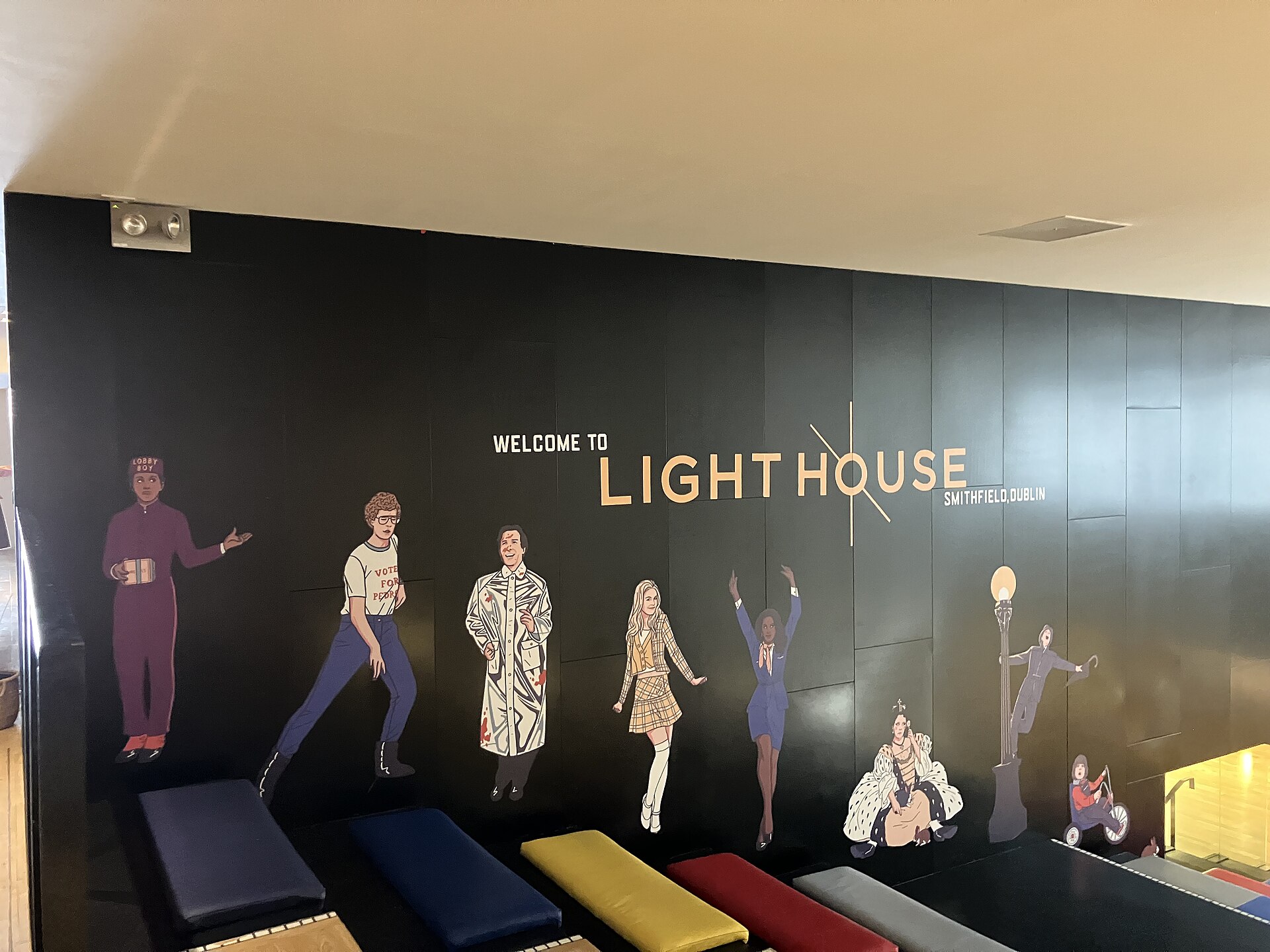 A film-character mural and colourful stepped seating inside Light House Cinema in Smithfield, Dublin, beneath the cinema welcome lettering.