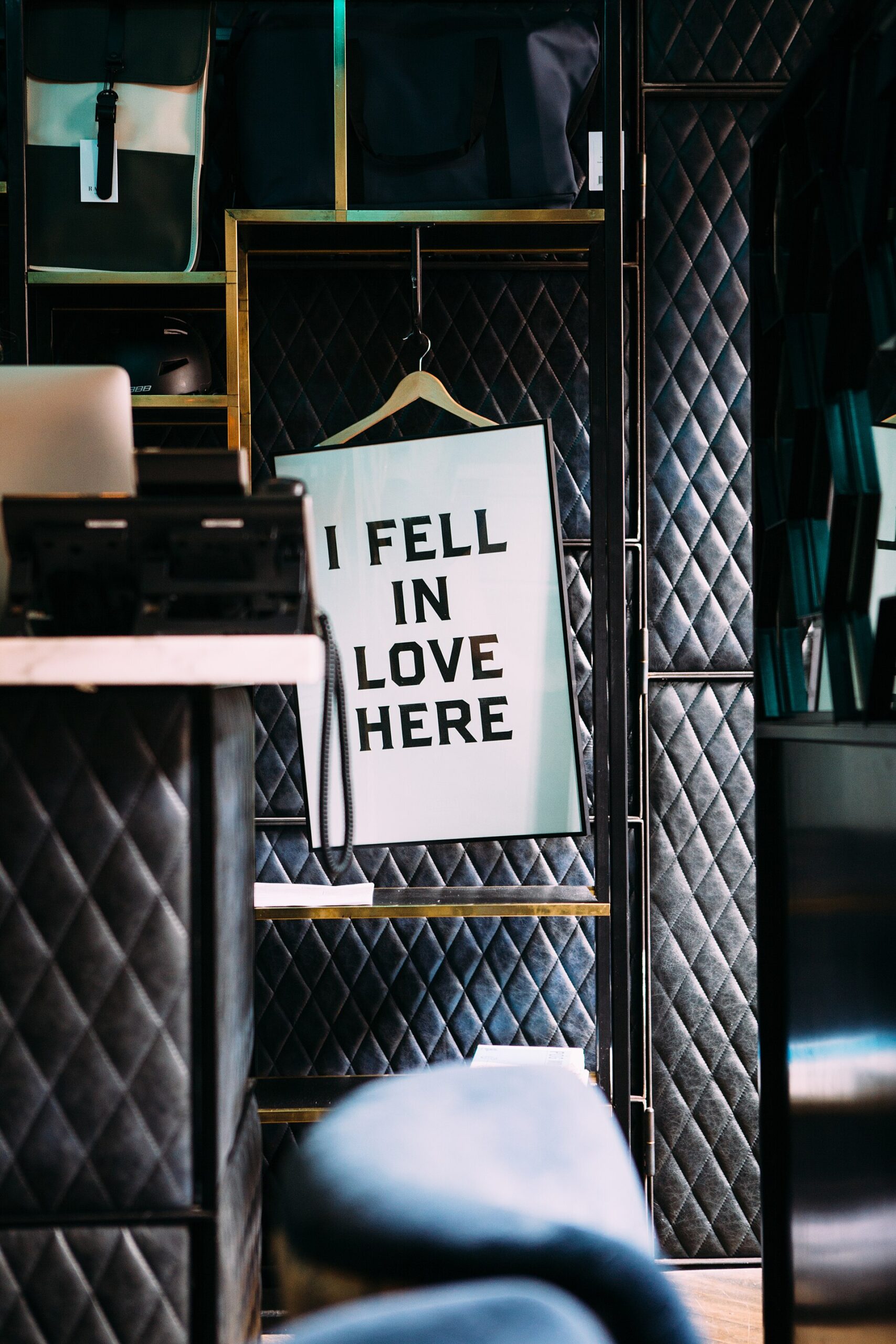 A framed slogan hangs against dark quilted upholstery and brass-edged shelving inside The Dean hotel in Dublin.