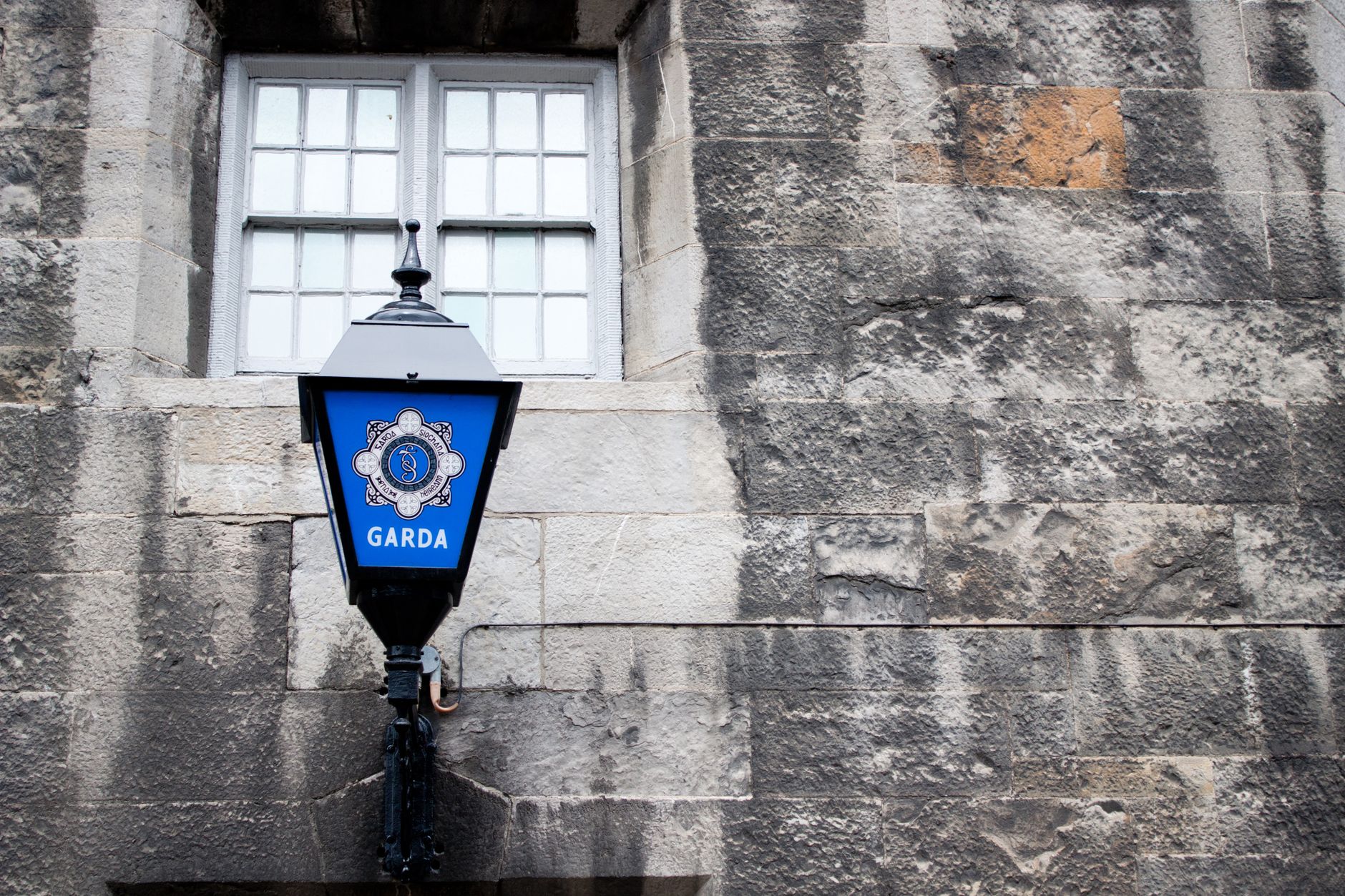 A blue Garda station lamp on a weathered stone wall in Dublin