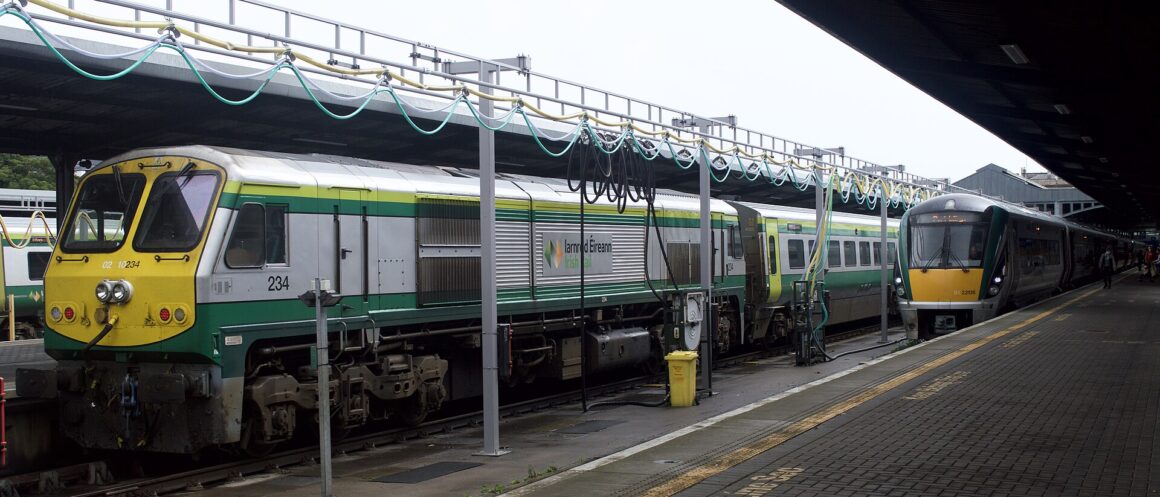 Green and silver Irish Rail trains stand beneath the platform canopies at Dublin Heuston station.