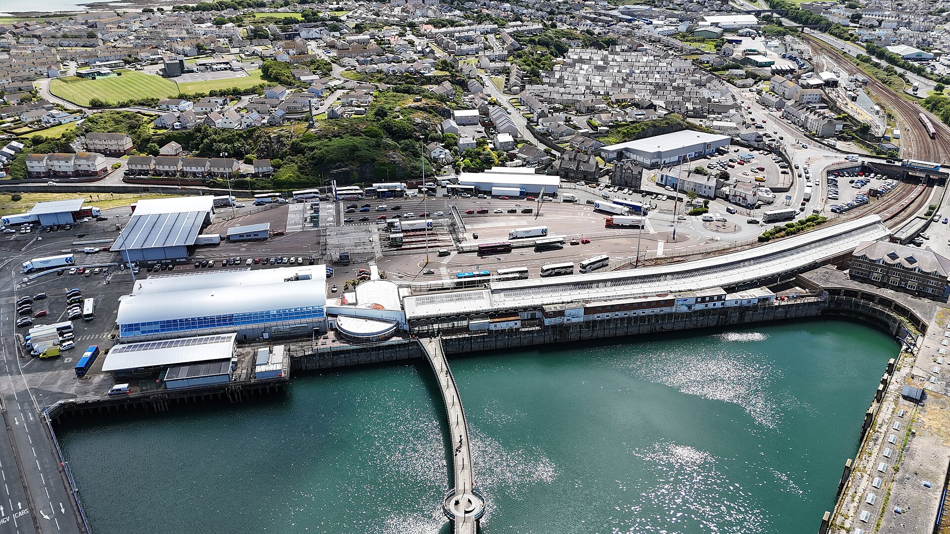 Holyhead railway platforms and the adjoining ferry terminal line the harbour, with tracks curving toward the town.