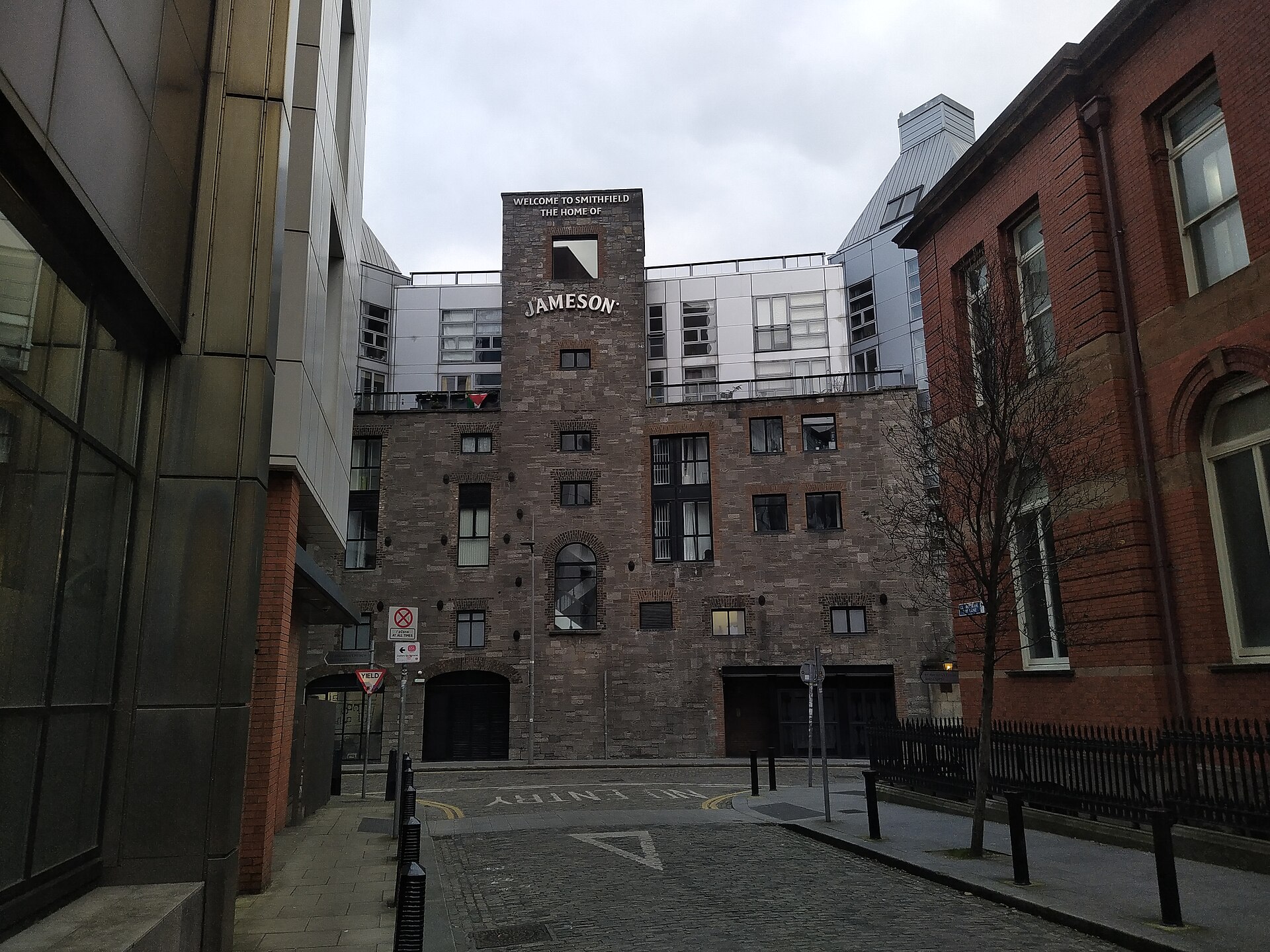 Jameson Distillery Bow St appears at the end of May Lane in Dublin, framed by neighbouring brick and metal buildings.