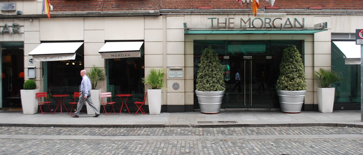 The Morgan Hotel in Dublin has a glass entrance canopy, potted shrubs, striped awnings and pavement tables.