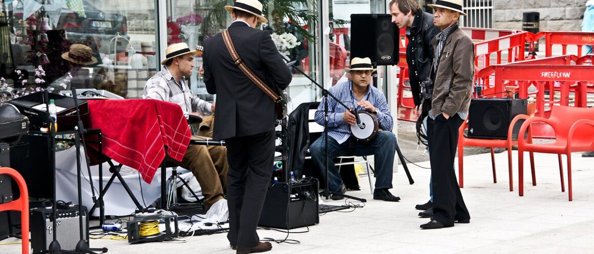 Musicians in straw boater hats play guitars and a hand drum at Bloomsday celebrations in Dún Laoghaire.