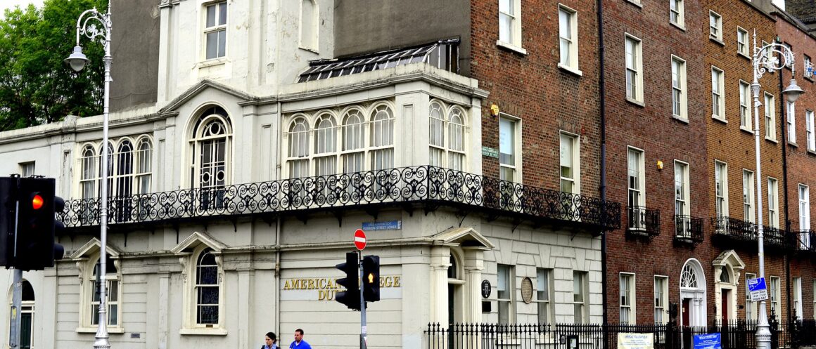 Oscar Wilde's childhood home at Merrion Square in Dublin, with an ornate balcony and pedestrians crossing beside its brick facade.