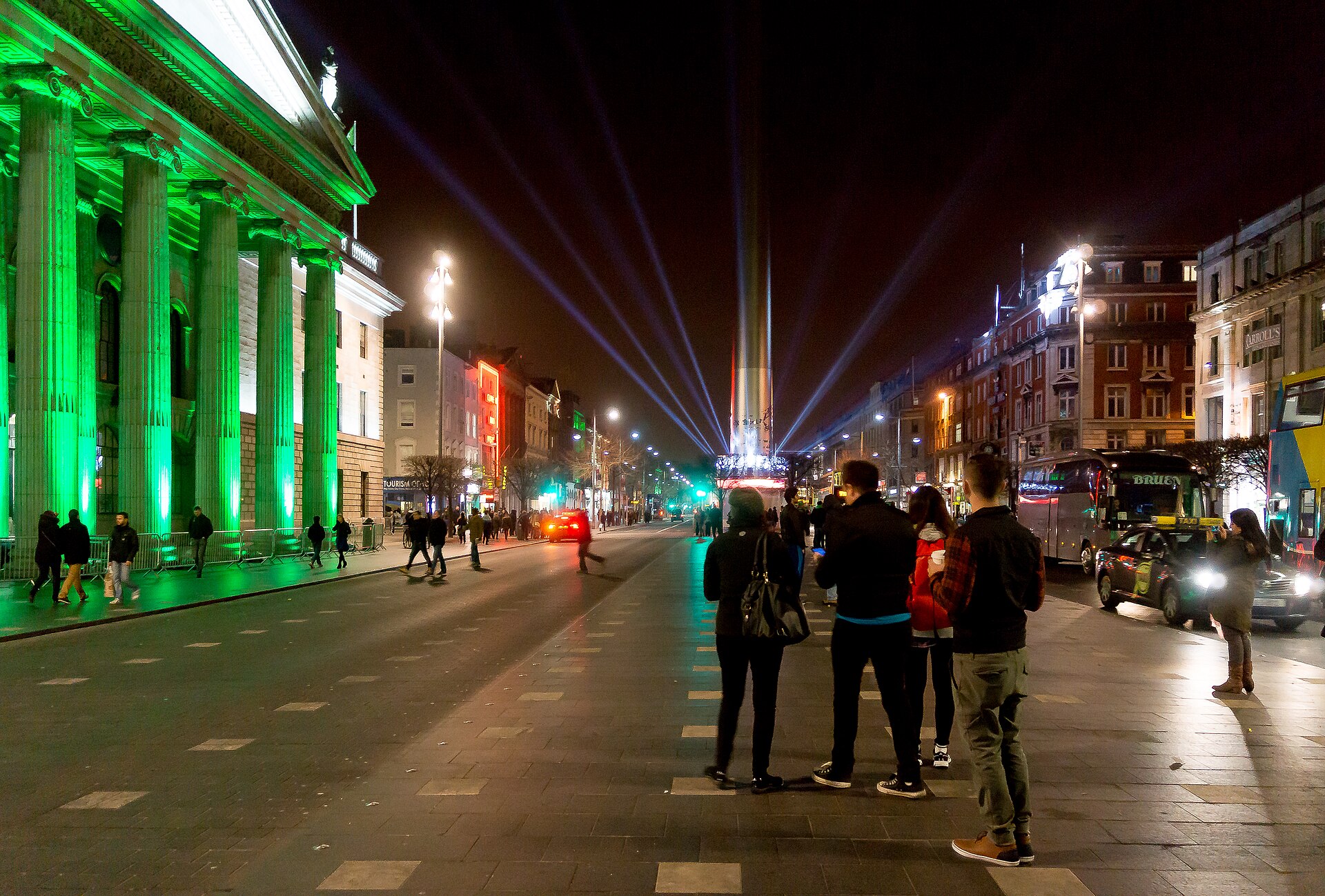 People watch beams of light around the Spire beside the green-lit General Post Office on Dublin's O'Connell Street.