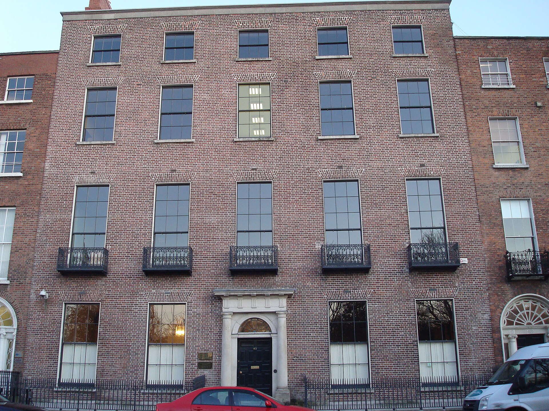 Red-brick Georgian houses on Dublin's Merrion Square, with sash windows, decorative iron balconies, fanlights and dark doors.