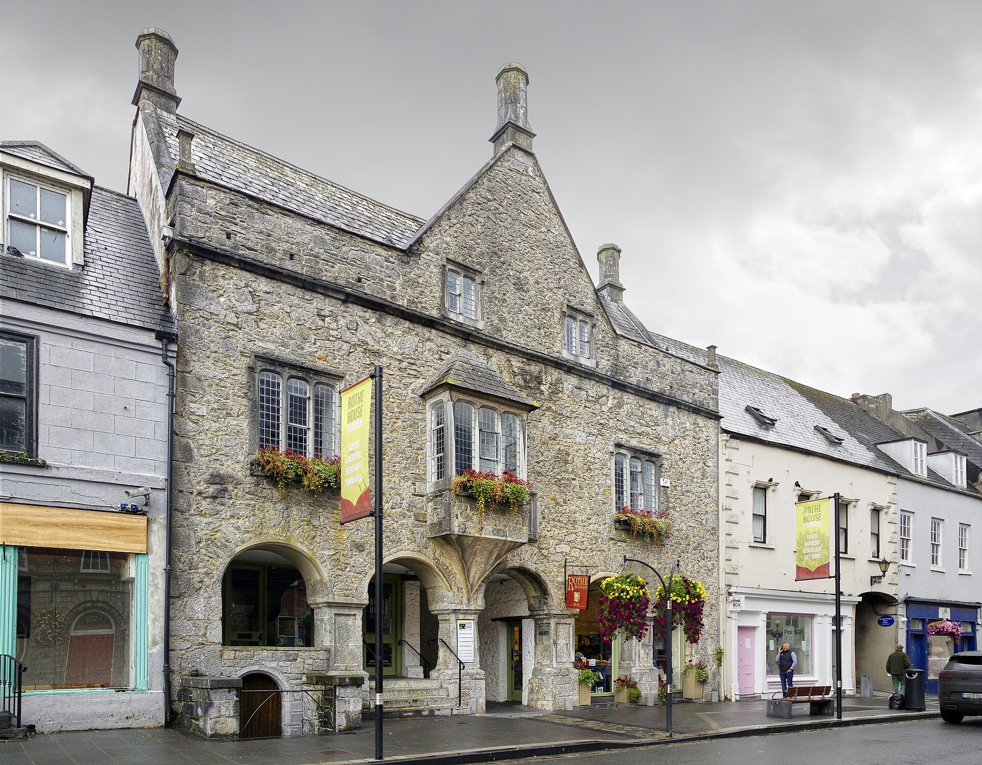 Rothe House's gabled stone frontage and arched openings face a Kilkenny street, with flower boxes beneath the leaded windows.