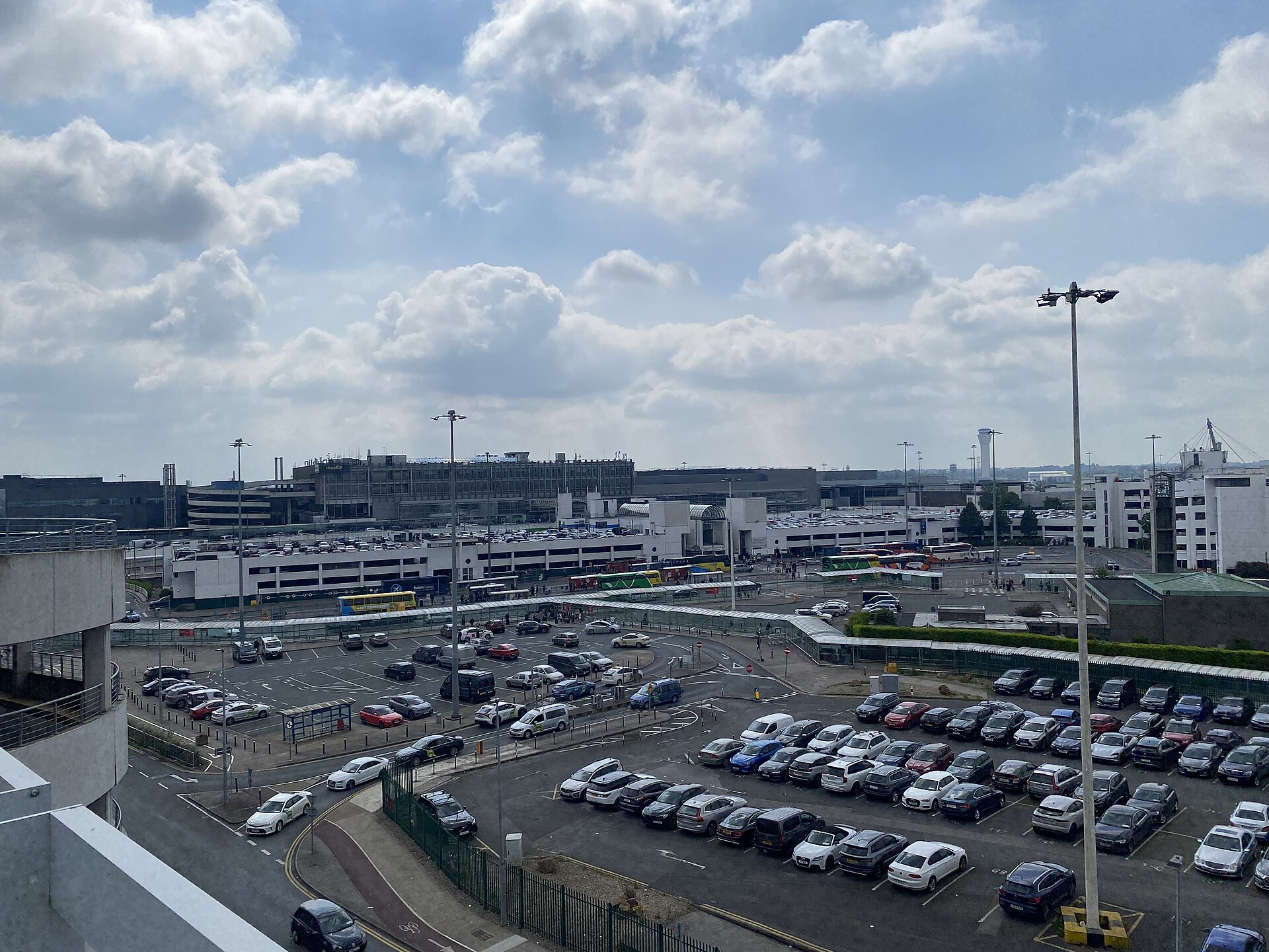 Rows of parked cars and access lanes outside Dublin Airport Terminal 1 under a cloudy sky.