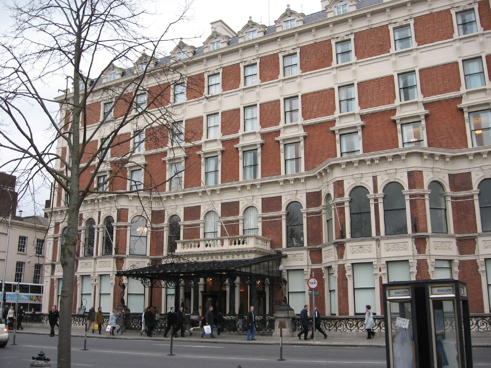 The Shelbourne Hotel in Dublin has an ornate red brick facade, pale stone window surrounds and a black entrance canopy.