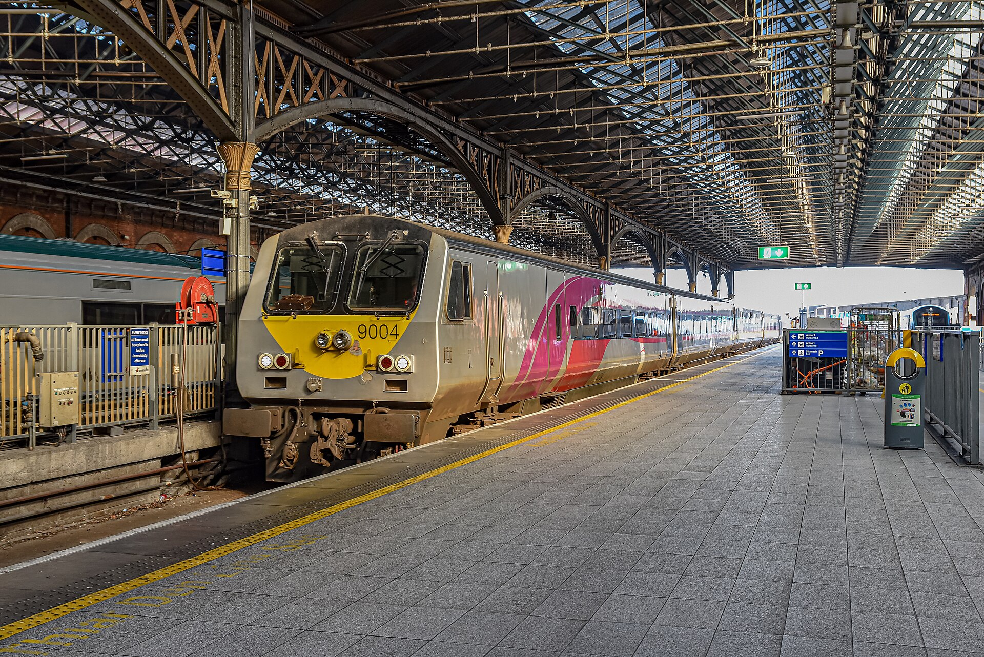 Silver and purple Enterprise coaches stand beneath the iron and glass roof at Dublin Connolly railway station.