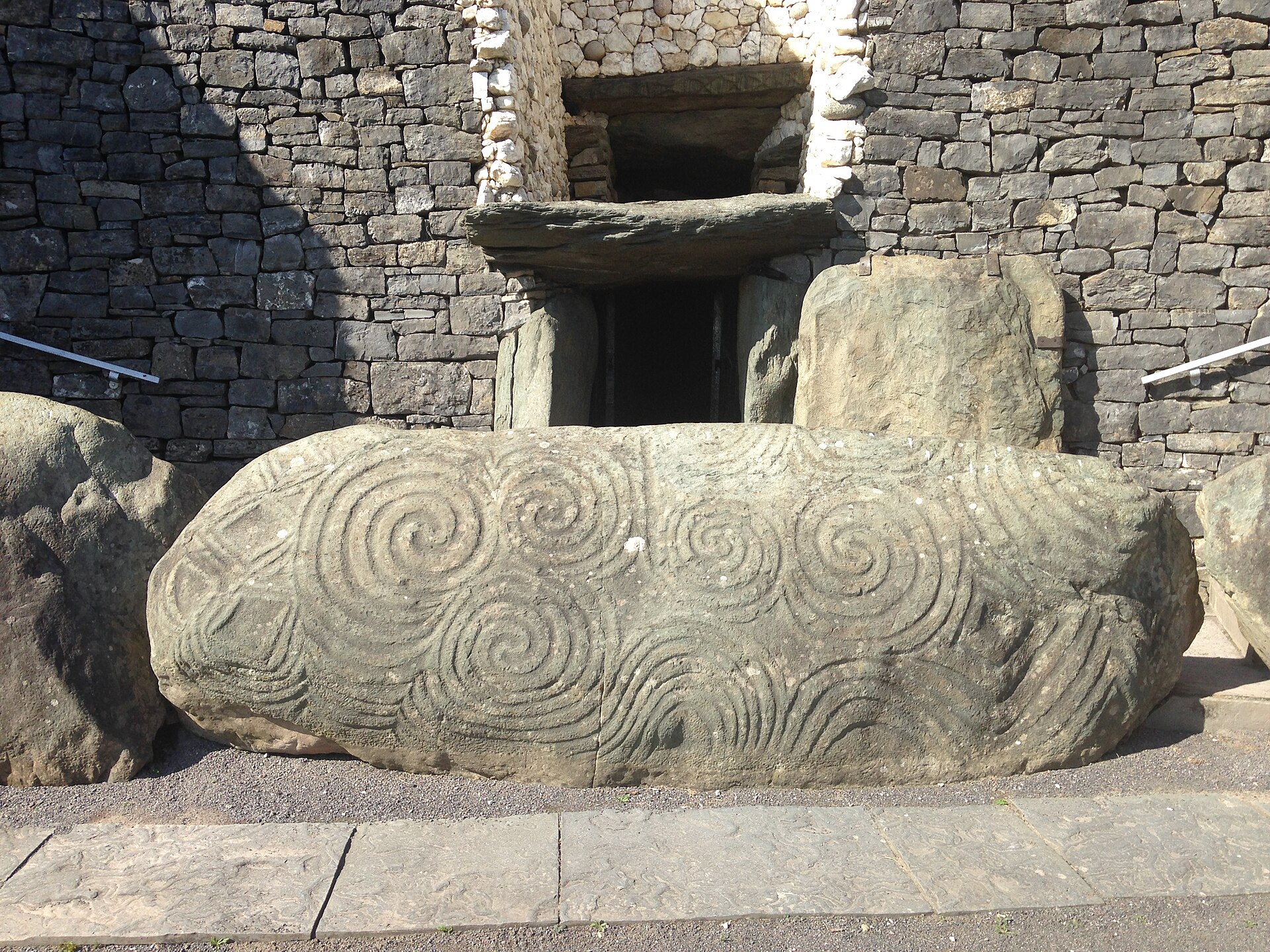 Spirals and geometric carvings cover the entrance stone at Newgrange, beneath the stone doorway and rectangular opening above it.