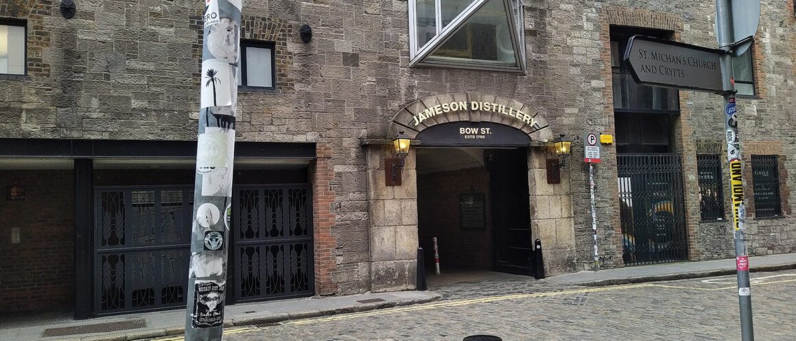 The stone entrance to Jameson Distillery Bow St in Dublin, with gold lettering above the arch and cobbles outside.
