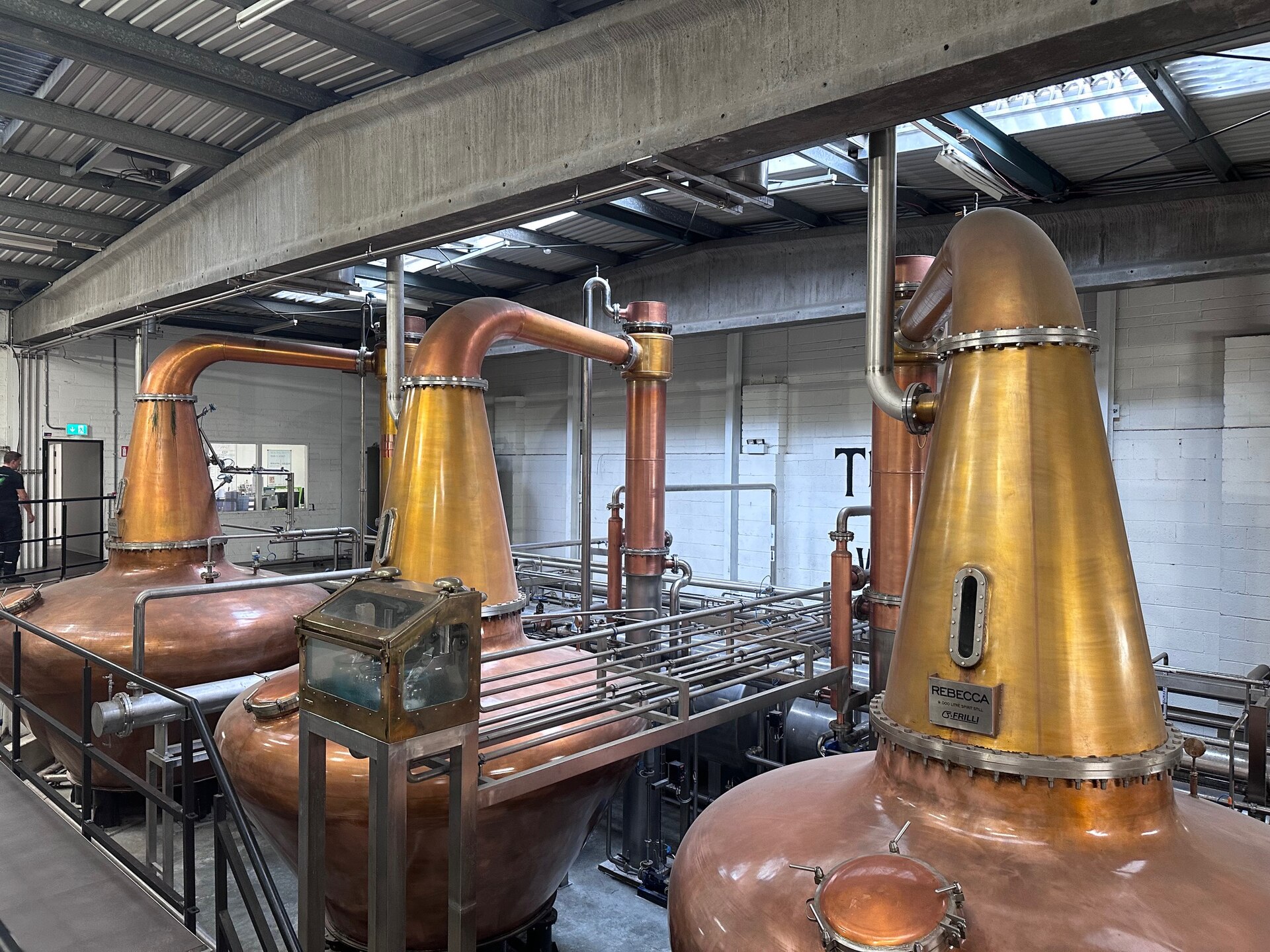 Three copper pot stills and their connecting pipes fill the industrial interior of Teeling Distillery in Dublin.