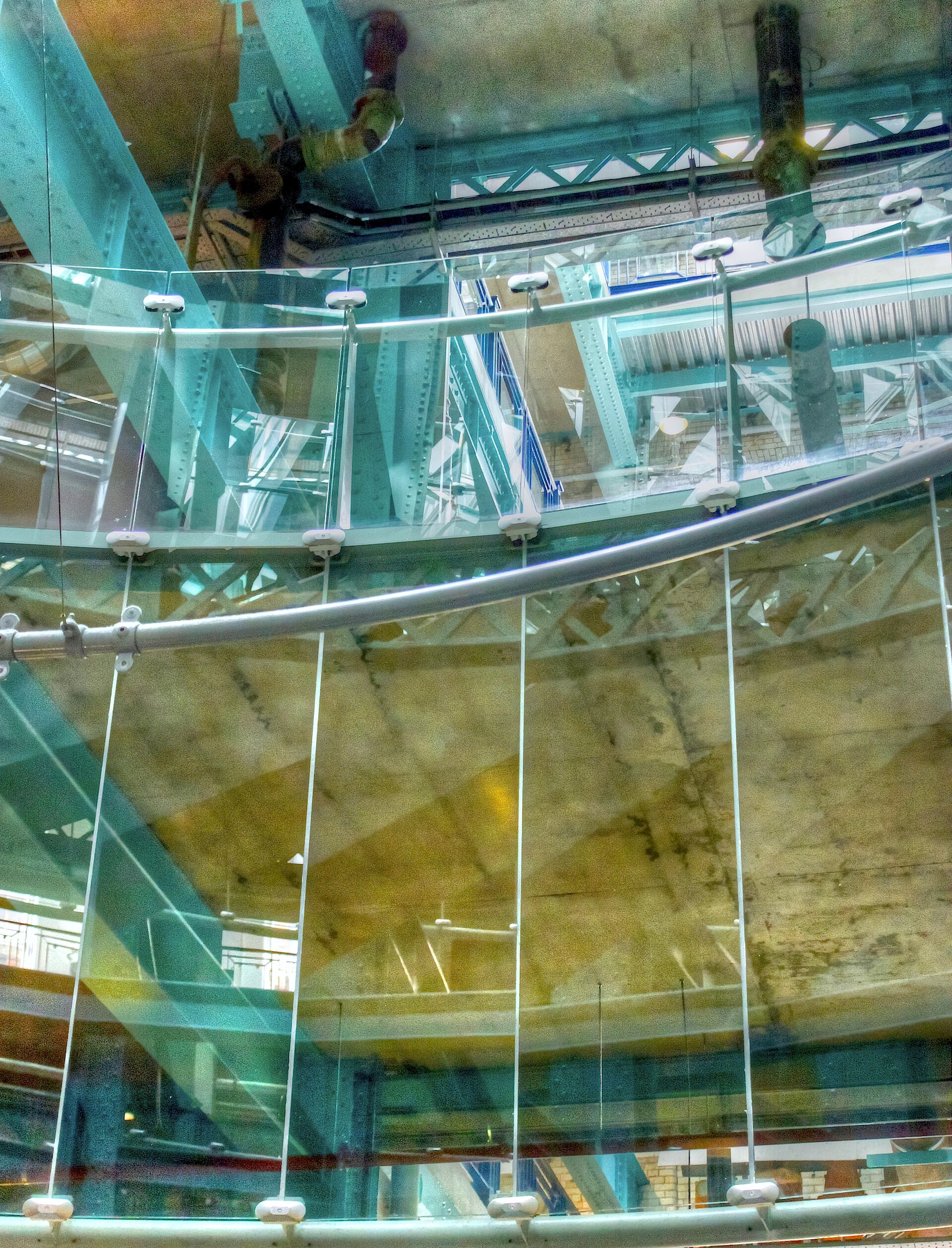 Turquoise steel columns and glass balustrades frame the multilevel industrial interior of the Guinness Storehouse in Dublin.