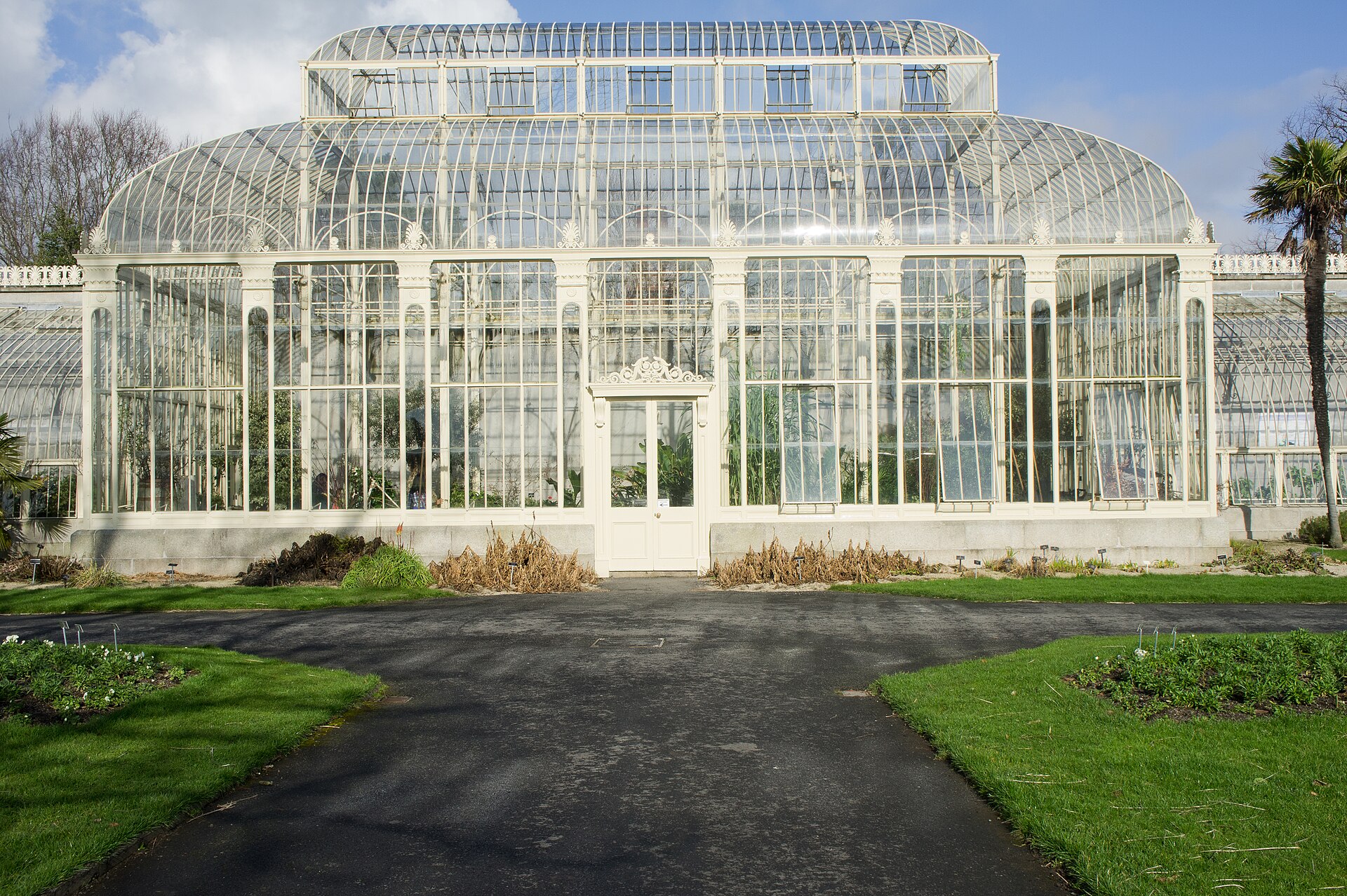 A white glasshouse pavilion faces a paved path between lawns at the National Botanic Gardens in Glasnevin.
